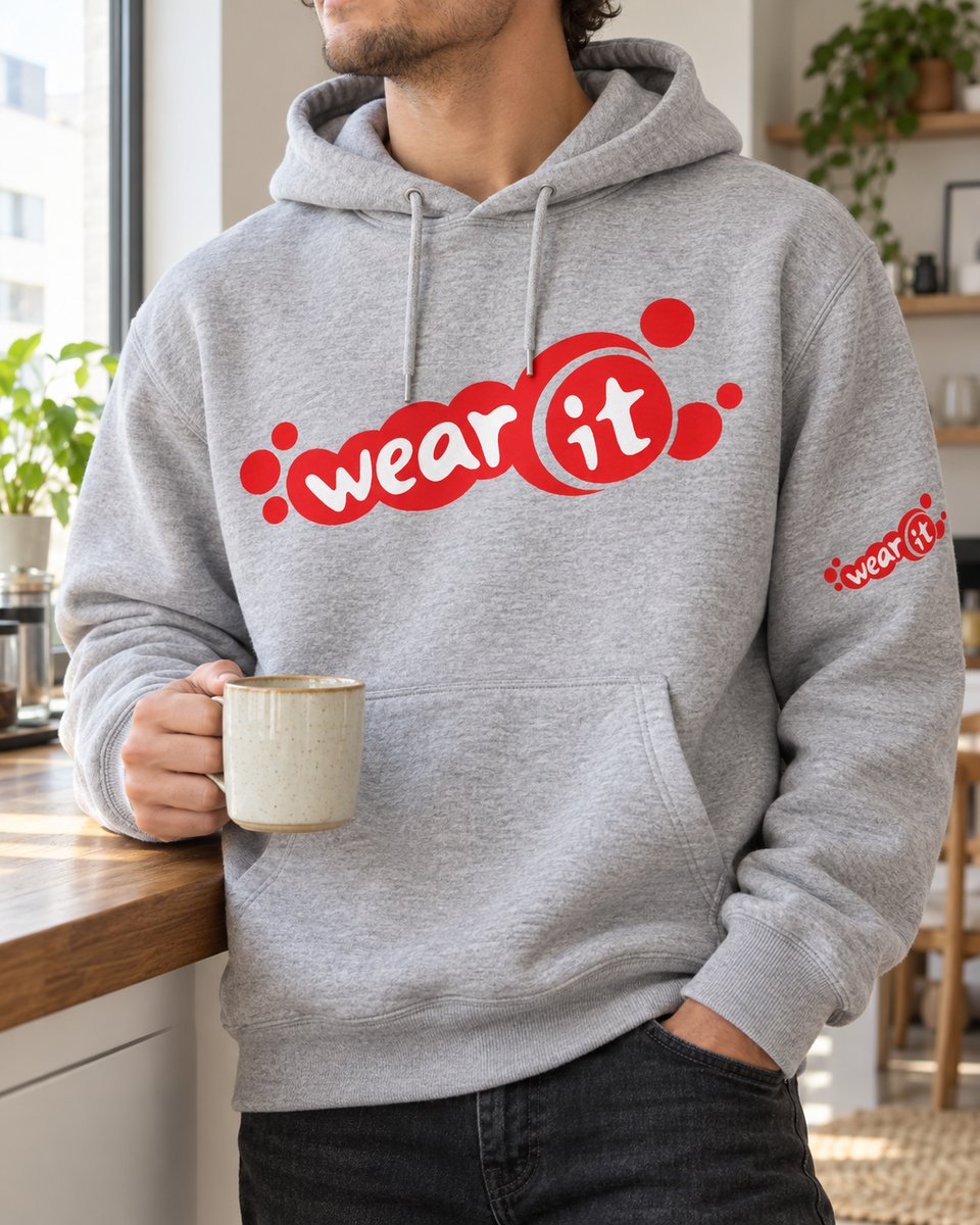 Homme accoudé à un plan de travail, tasse à la main, en sweat à capuche gris chiné Wear It