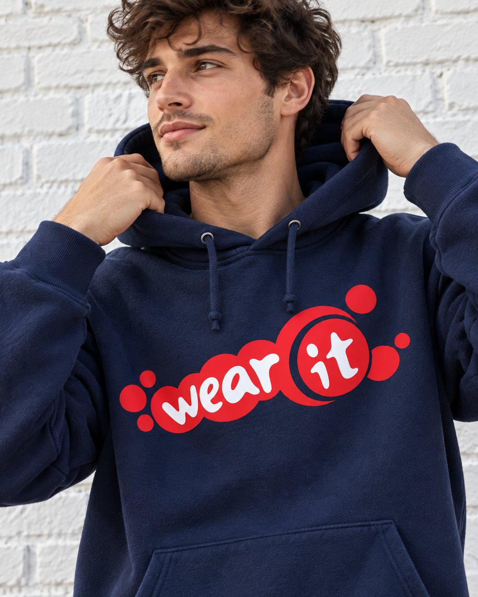 Homme qui ajuste la capuche de son sweat bleu marine Wear It devant un mur de briques blanches
